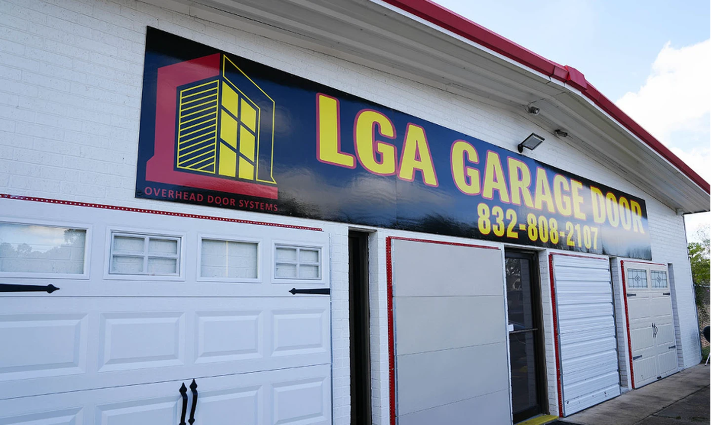 LGA Garage Door showroom exterior featuring various garage door styles, including a white carriage-house door, and a large black sign with the phone number 832-808-2107